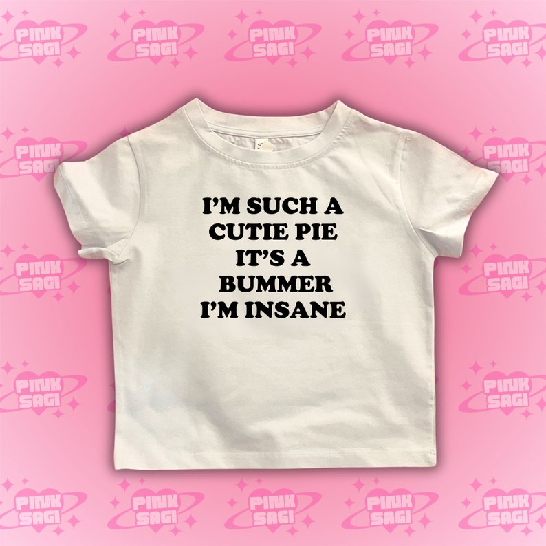 May include: White t-shirt with black text that reads "I'm such a cutie pie it's a bummer I'm insane".