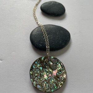 May include: A silver chain necklace with a round iridescent abalone shell pendant.