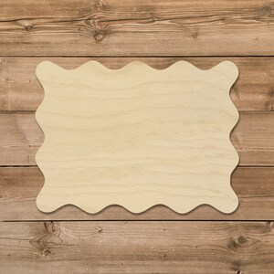 May include: A blank, wavy-edged wooden sign with a light brown wood grain. The sign is sitting on a brown wooden background.