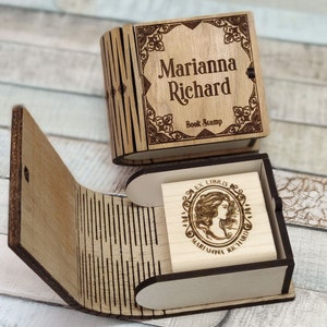 以下が含まれることがあります： 木製のブックスタンプボックス。蓋には「Marianna Richard Book Stamp」という個人名入り。ボックスが開いており、木製のスタンプが露出。スタンプには「Ex Libris Marianna Richard」という文字と装飾的なデザインが刻まれている。
