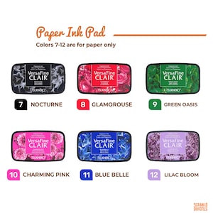 May include: Six VersaFine Clair pigment ink pads in a range of colours, including black, red, green, pink, blue, and purple. Each rectangular pad features a floral design and is labelled with a colour name and number. The text "Paper Ink Pad" is at the top.