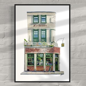May include: Watercolor painting of a pub called "Marksman" with brick and white facade, green window frames, and a hanging sign. The artwork is framed in a black border and set against a white brick wall.