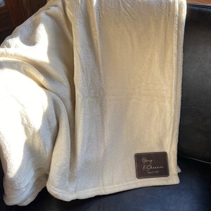 May include: A white plush throw blanket with a brown leather patch that says "Greg & Shannon June 2, 1990".
