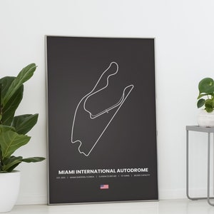 Puede incluir: Un p&oacute;ster negro enmarcado con un contorno blanco del circuito del Miami International Autodrome. El p&oacute;ster incluye el nombre del circuito, la ubicaci&oacute;n y otros detalles en texto blanco. Una peque&ntilde;a bandera americana en la parte inferior.
