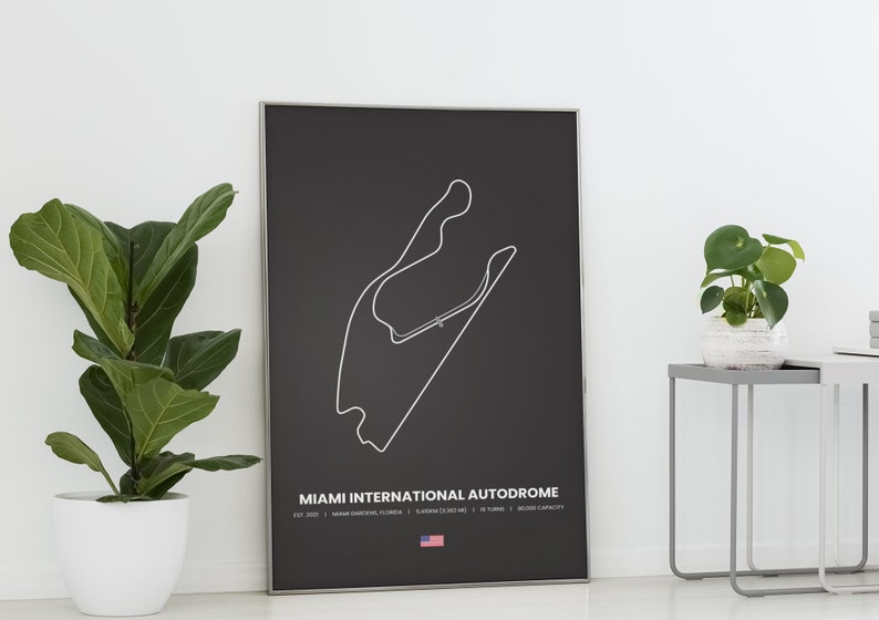Puede incluir: Un p&oacute;ster negro enmarcado con un contorno blanco del circuito del Miami International Autodrome. El p&oacute;ster incluye el nombre del circuito, la ubicaci&oacute;n y otros detalles en texto blanco. Una peque&ntilde;a bandera americana en la parte inferior.