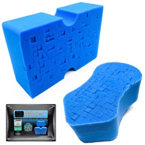 May include: Two blue car wash sponges. One sponge is a rectangular block with a cut-out section. The other sponge is shaped like a teardrop. Both sponges have a textured surface. The packaging for the sponges is visible in the bottom left corner of the image. The packaging is black with white text that reads "PREMIUM FOAM CAR WASH SPONGES".