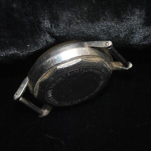 Pu&ograve; includere: Primo piano di un orologio da polso vintage color argento. La cassa dell'orologio &egrave; rotonda e presenta segni di usura. I supporti del cinturino sono visibili. Il quadrante dell'orologio riporta la scritta "FORT SUPERAUTOMATIC".