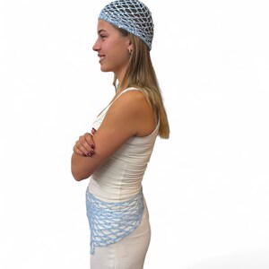 May include: A light blue crochet beanie and a matching light blue crochet triangular scarf. Both items feature an open-knit net pattern with small, reflective sequins woven throughout the yarn, creating a subtle shimmer against the light blue color.
