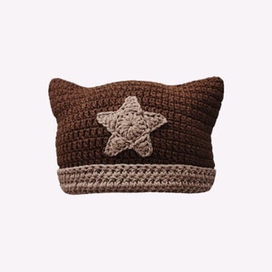 May include: Brown crocheted hat with a beige star on the front.
