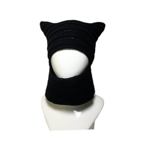 May include: Black crocheted cat ear hat with a face opening and a neck warmer. The hat is on a white mannequin.