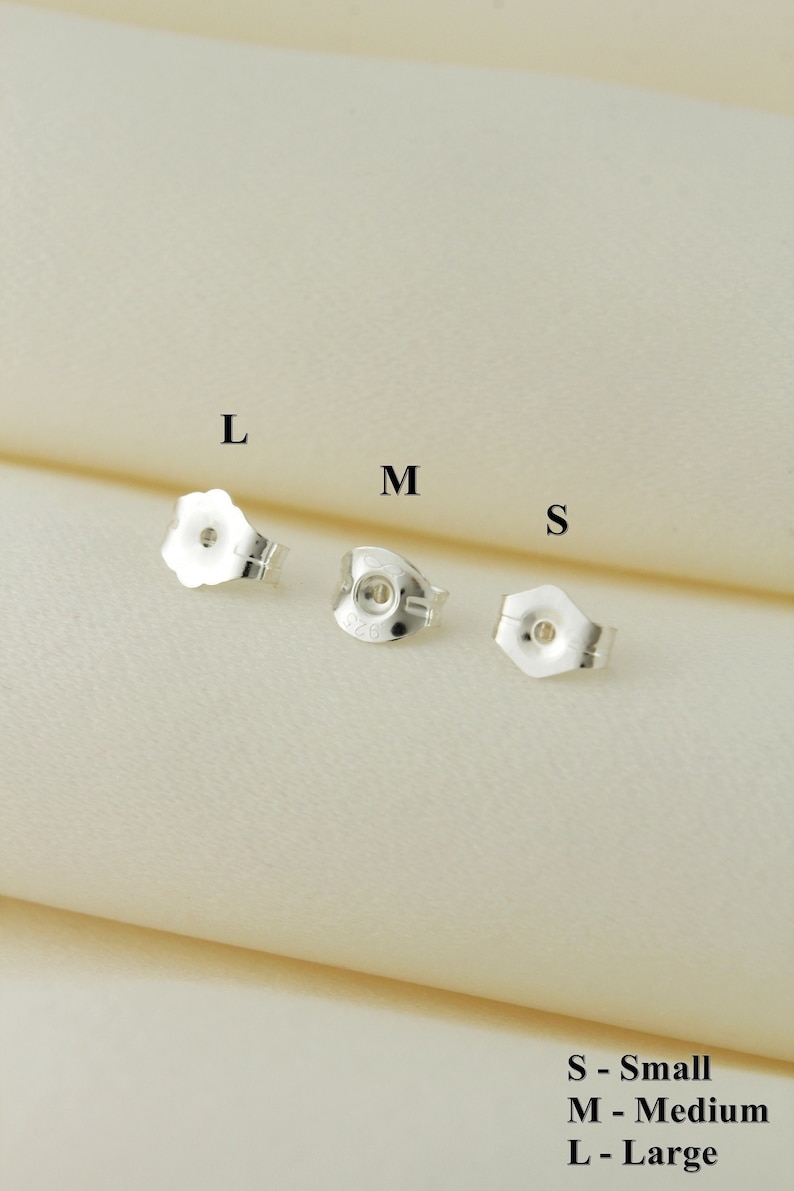 May include: Three silver earring backs in different sizes: small, medium, and large. The backs are labeled with the letters S, M, and L.