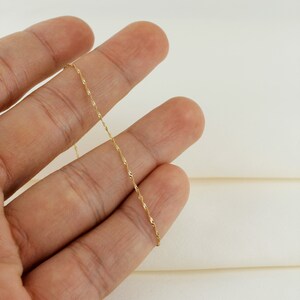 Op de afbeelding: Een dunne gouden ketting met een delicaat, gedraaid ontwerp.