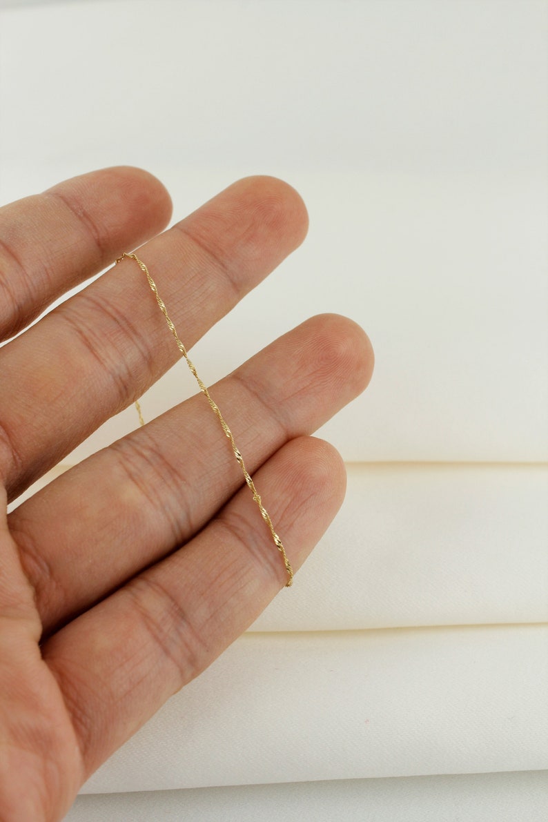 Op de afbeelding: Een dunne gouden ketting met een delicaat, gedraaid ontwerp.