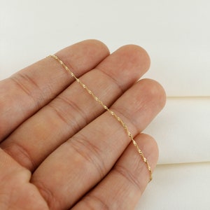 Op de afbeelding: Een dunne gouden ketting met een delicaat, gedraaid ontwerp.