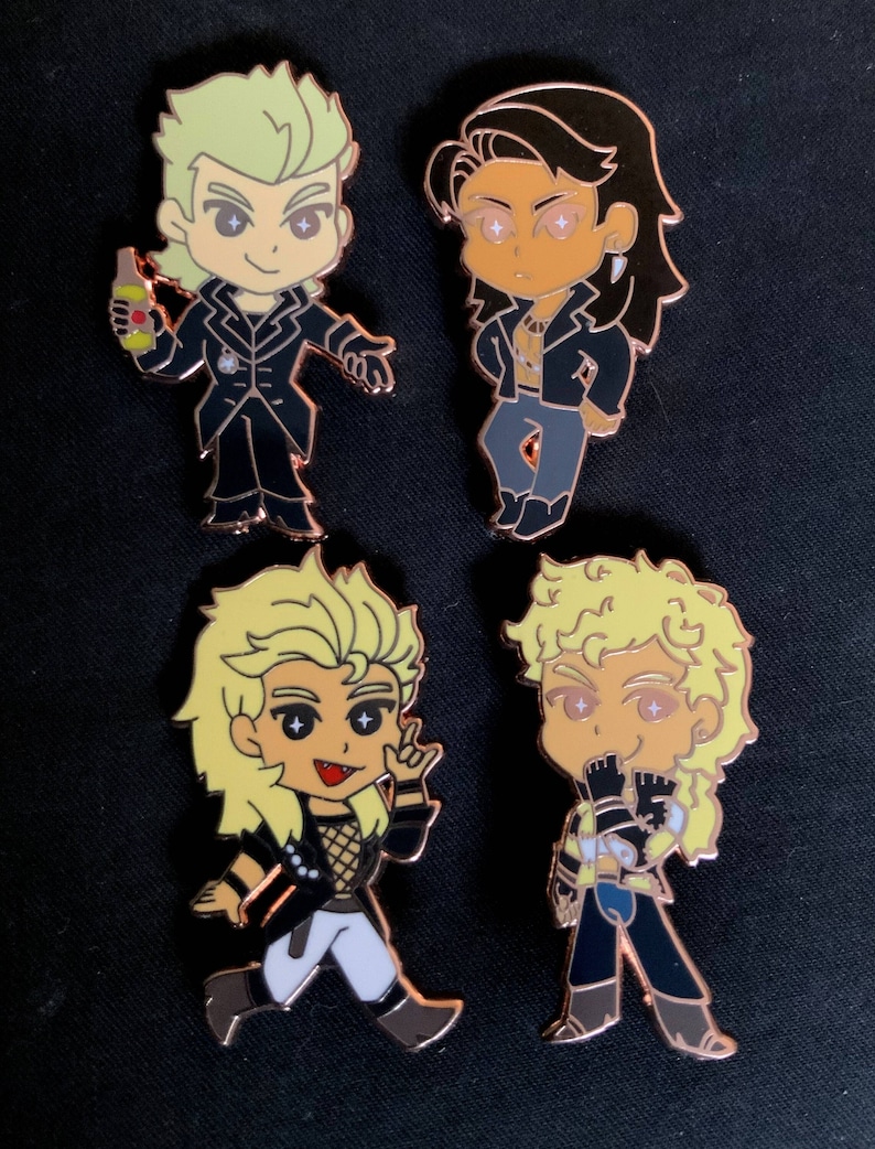 May include: Four enamel pins featuring cartoon characters with copper-colored outlines. The characters have blonde and brown hair, wearing black jackets and pants. One pin shows a character holding a bottle. The pins are on a black background.
