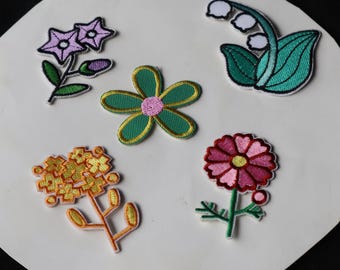 May include: Six embroidered iron-on patches featuring different flower designs. The patches are in various colors, including pink, green, yellow, and white.