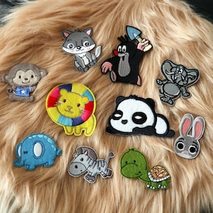 May include: A collection of embroidered animal patches, including a monkey, wolf, lion, panda, elephant, zebra, turtle, and rabbit. The patches feature bright colors and detailed stitching, perfect for decorating clothing or accessories.