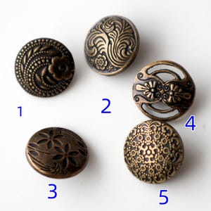 May include: Five antique bronze buttons with detailed floral and swirl patterns. Each button features a unique design, including a flower, swirling leaves, and openwork. These decorative buttons are suitable for sewing and craft projects.