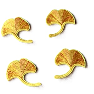 May include: Four yellow ginkgo leaf embroidered patches. The leaves are a light yellow with a darker yellow center. The leaves are all the same size and shape.