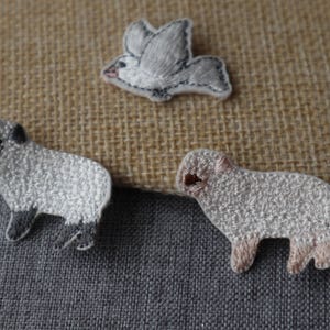 May include: Three embroidered patches: a white dove, a white lamb with black hooves, and a white lamb with brown hooves.