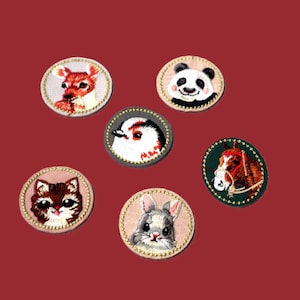 May include: A collection of embroidered animal patches, each circular in shape. The patches depict a deer, panda, bird, cat, rabbit, and horse. They have detailed designs and decorative borders, set against a red background.