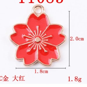 May include: A red enamel flower charm with a gold-tone finish. The charm is 1.8 inches wide and 2 inches tall.  The charm has a loop at the top for attaching to a necklace or bracelet.