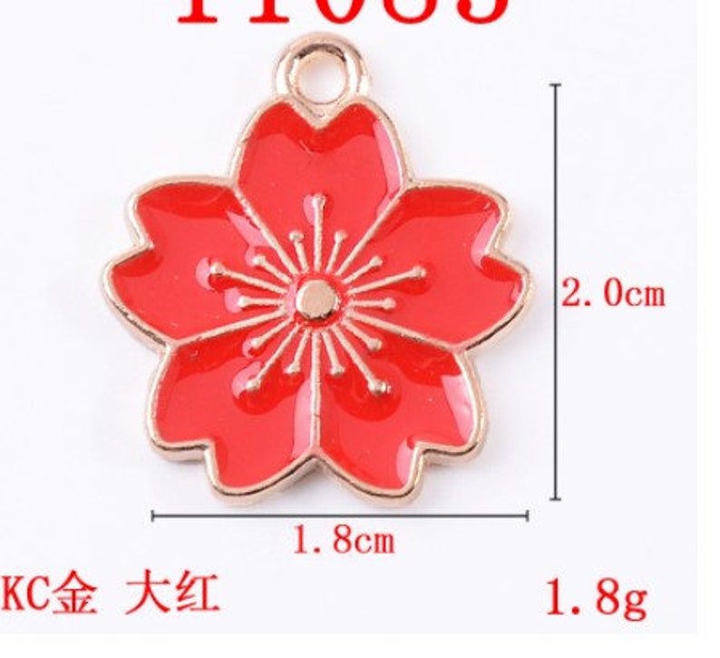 May include: A red enamel flower charm with a gold-tone finish. The charm is 1.8 inches wide and 2 inches tall.  The charm has a loop at the top for attaching to a necklace or bracelet.