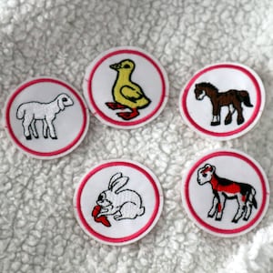 May include: Set of five embroidered patches featuring farm animals: a lamb, duckling, pony, rabbit, and goat. Each patch is circular with a white background, a red border, and detailed animal illustrations. These patches are suitable for clothing or craft projects.