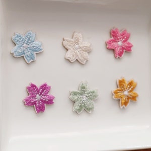 Peut inclure: Six patchs brodés en forme d'étoile à cinq branches, dans différentes couleurs, notamment bleu clair, blanc, rose, magenta, vert et jaune.