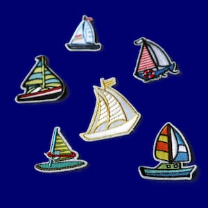 May include: A collection of six embroidered sailboat patches featuring various designs. The patches include boats with striped, solid, and multi-colored sails in shades of blue, red, yellow, white, and green, each with detailed stitching and distinct hull shapes.