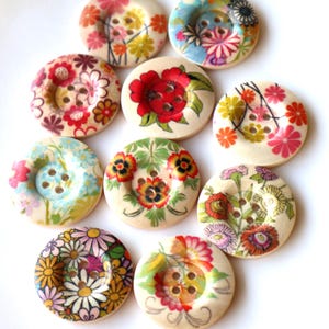 May include: Assortment of 10 round wooden buttons with floral designs. The buttons are in various colours, including red, pink, blue, yellow, and green. Each button has four holes.