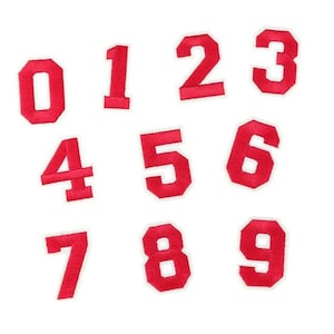 May include: Ten red felt numbers, 0 through 9, with white outlines. The numbers are arranged in two rows, with the numbers 0, 1, 2, and 3 in the top row and the numbers 4, 5, 6, 7, 8, and 9 in the bottom row.