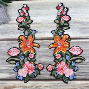 May include: Two embroidered floral patches featuring pink, orange, and blue flowers. The patches include a large orange lily and smaller pink roses.