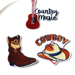 Peut inclure: Trois patchs brodés thermocollants sur le thème de la musique country. Les patchs représentent une guitare acoustique rouge, une botte de cowboy marron et un chapeau de cowboy avec le mot "COWBOY" au-dessus. Le patch de la guitare comprend également le texte "Country Music".