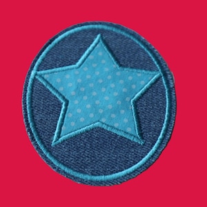 May include: A circular embroidered patch featuring a dark blue denim-textured background with a central light blue star. The star is decorated with a white polka dot pattern and is outlined with light blue thread, matching the circular border.