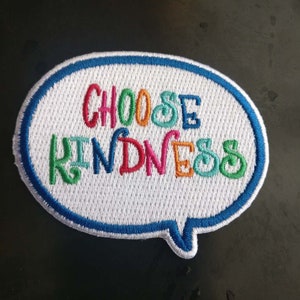 May include: A white, speech bubble-shaped patch with a blue border. The words "CHOOSE KINDNESS" are embroidered in colourful letters.