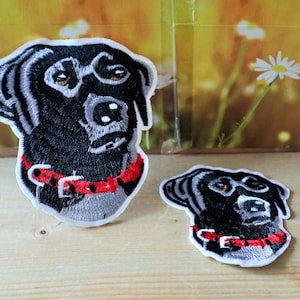 May include: Two black embroidered iron-on patches of a dog wearing a red collar. The larger patch has a more detailed design and the smaller patch has a simpler design.