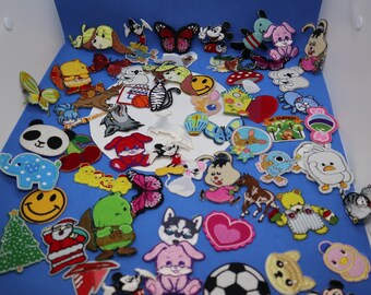 May include: A collection of colorful embroidered iron-on patches featuring various cartoon animals, characters, and designs. The patches are on a blue background.