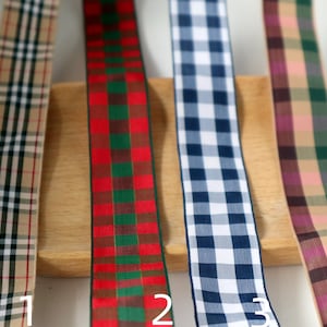 Peut inclure: Quatre échantillons de ruban à carreaux différents. Le premier ruban est beige, marron et noir. Le deuxième ruban est rouge, vert et marron. Le troisième ruban est bleu et blanc. Le quatrième ruban est marron, rose et vert.