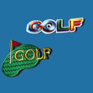 May include: Two embroidered patches. The top patch features the word GOLF in multi-coloured, gradient-style block letters with a white border. The bottom patch depicts a green golf course shape with a red flag and the word GOLF in gold lettering.