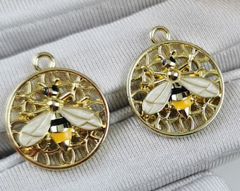 May include: Two gold-tone bee charms with a white and yellow enamel bee design. The bee is surrounded by a delicate, openwork design.