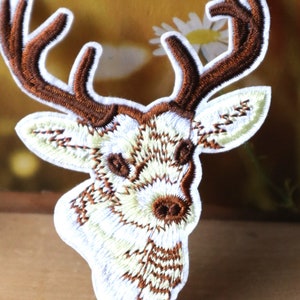 May include: White embroidered iron-on patch of a brown deer head with antlers.