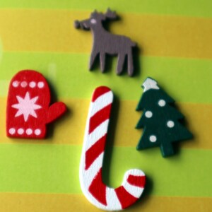 May include: A set of five wooden Christmas ornaments. The ornaments are a red and white candy cane, a green Christmas tree with white dots, a red mitten with white snowflakes, and a gray reindeer.