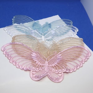 May include: Three layered butterfly appliques in shades of pink, beige, and blue. The appliques are made of delicate lace and are perfect for adding a touch of whimsy to any project.