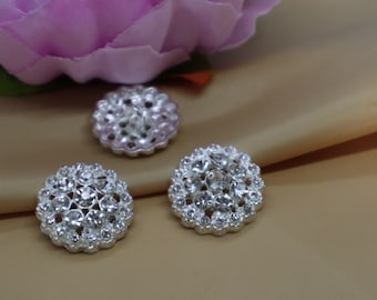 May include: Three silver-toned buttons with clear rhinestone embellishments. The buttons are round and have a scalloped edge.