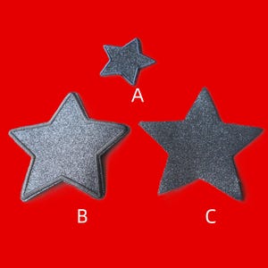 May include: Three star-shaped patches with a dark grey glittery finish. The patches are labelled with white letters A, B, and C. Patch A is the smallest, while patches B and C are larger and feature a distinct stitched border around the edges.
