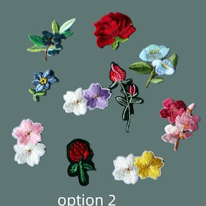 May include: A collection of embroidered floral patches featuring various designs including red roses, blue blossoms, pink and white cherry blossoms, and green leaves. The text "option 2" is printed in white at the bottom of the image.
