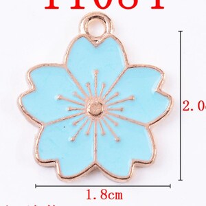 May include: A light blue enamel flower charm with a gold-tone finish. The charm is 1.8 inches wide and 2 inches tall.