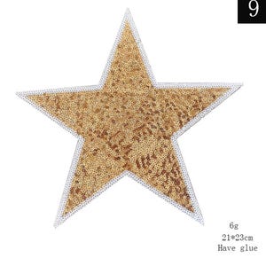 May include: Gold star-shaped sequin patch with a white outline. The patch is 21 cm by 23 cm and has glue on the back.