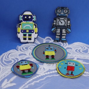 May include: Embroidered robot patches in various designs. The patches feature robots in shades of blue, yellow, grey, and red, with intricate stitching details. The patches are on a blue background with a white lace overlay.